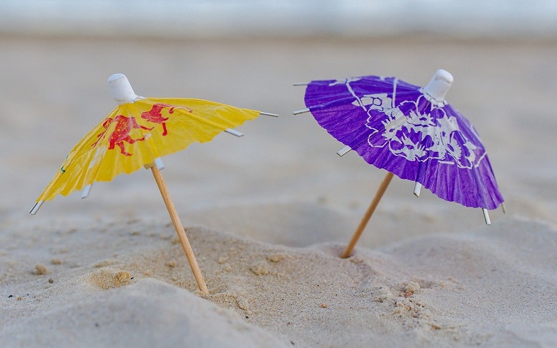Due ombrellini da sole sulla sabbia per rappresentare i raggi UV-A e UV-B