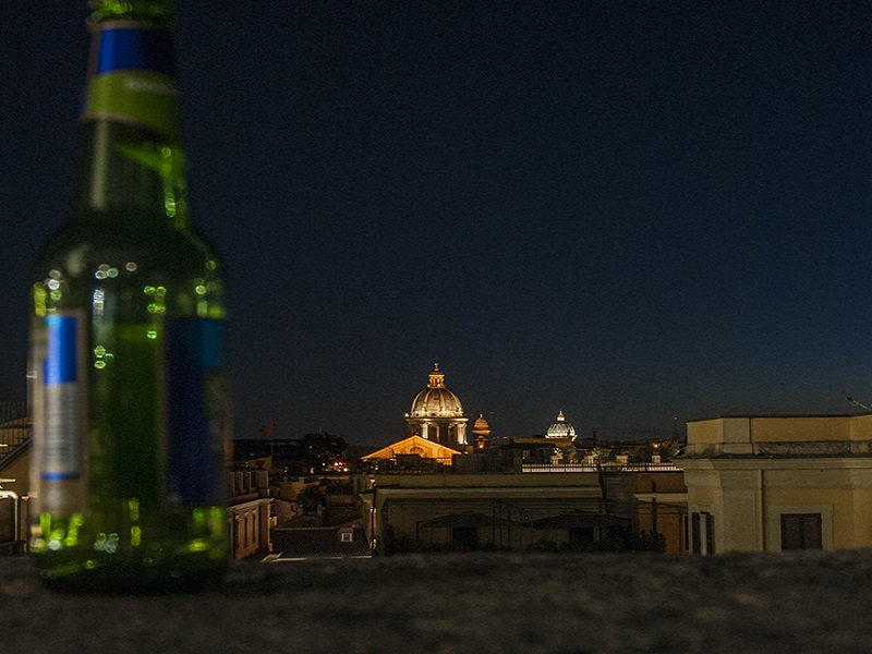 nell'immagine troviamo una bottiglia di birra in primo piano e la cupola di San Pietro a Roma in sfondo